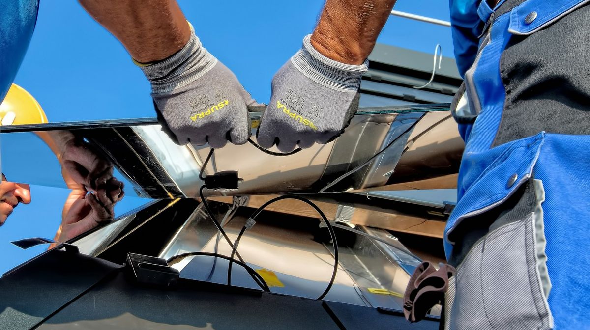 Montage eines Solarmoduls mit Schutzhandschuhen